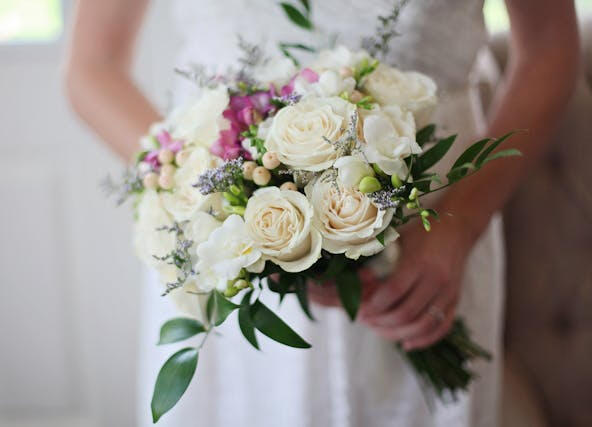 Bride in white wedding dress holding flower arrangement